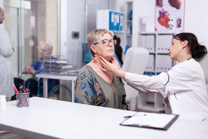 A female doctor examining a senior patient neck during a medical consultation.