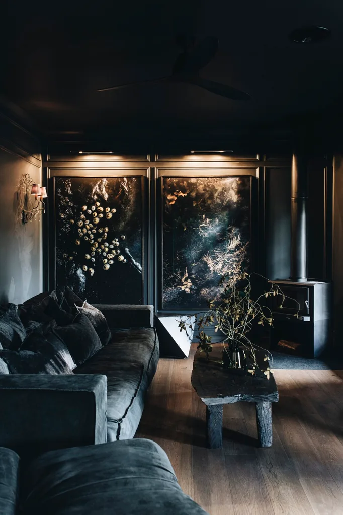 A dark and moody lounge room with charcoal-coloured walls and dark floral paintings
