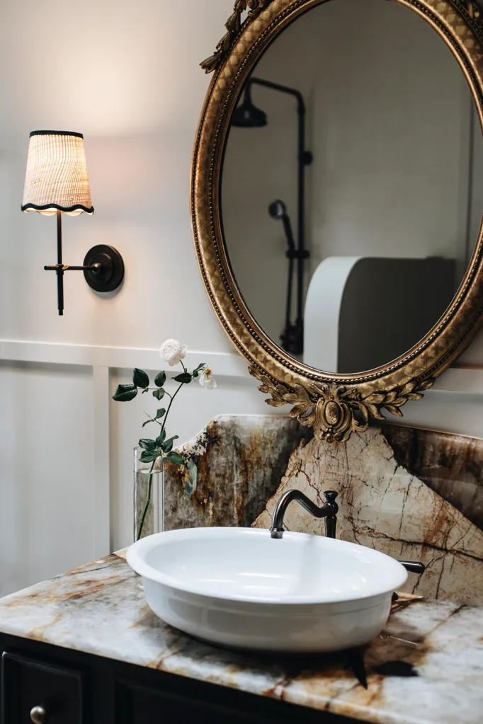 A marble vanity with a gold round mirror