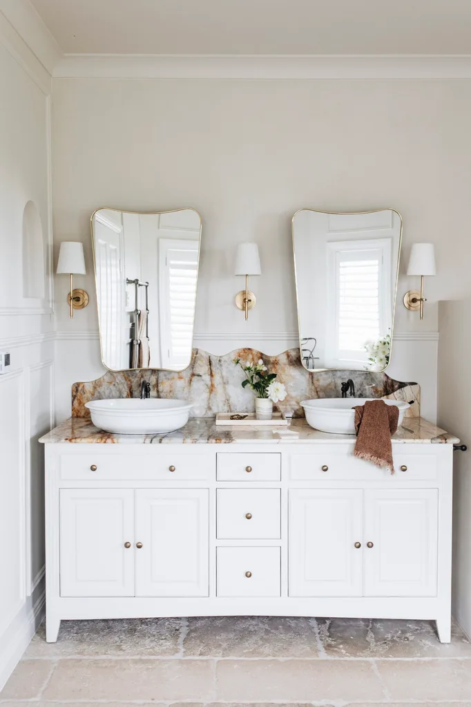 A double vanity with a marble benchtop and wall sconces