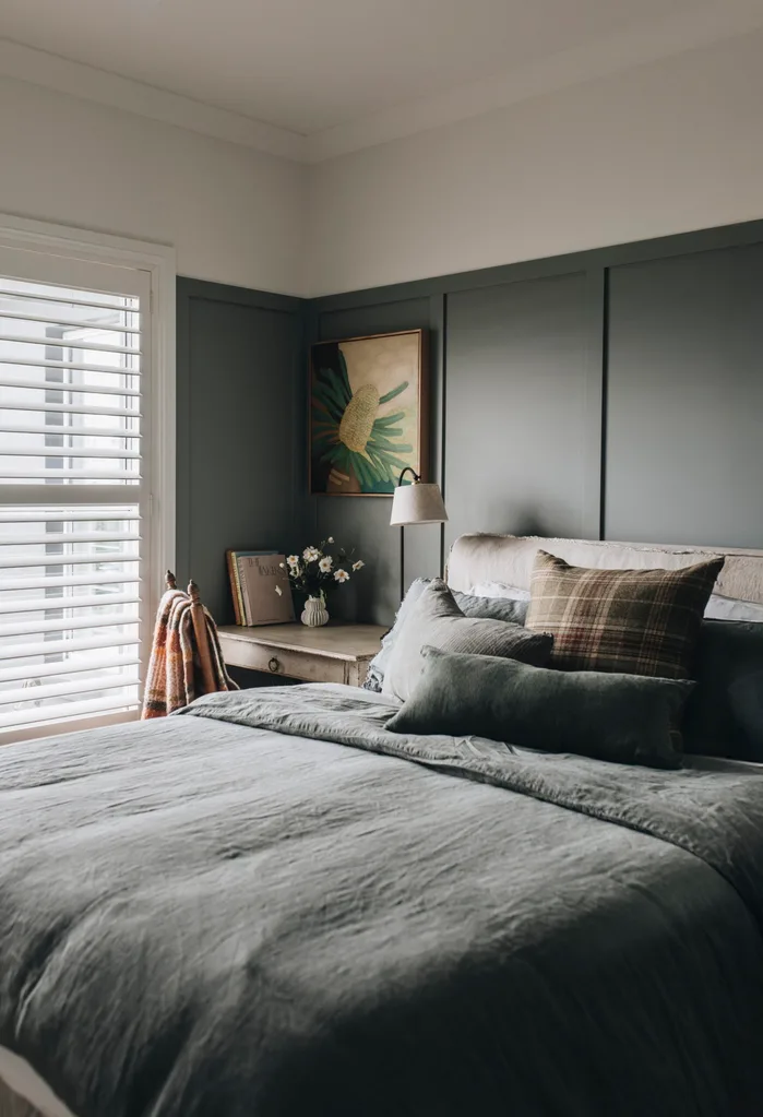 A grey-green coloured bedroom with linen bedding and an antique desk