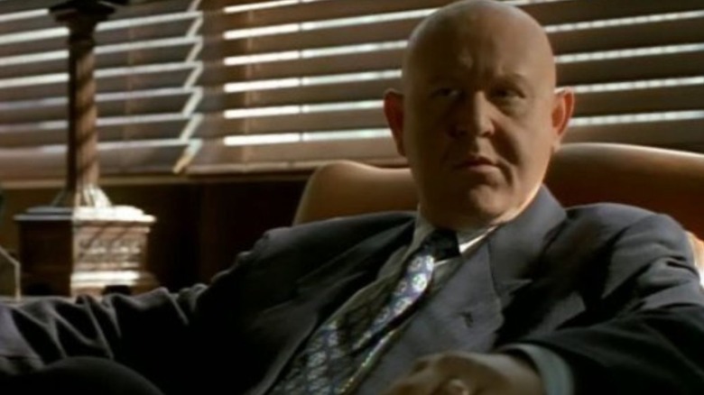 Daniel Benzali as Ted Hoffman, sitting in a chair in Murder One.