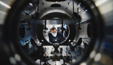 Masked technician inspects equipment at Amazon Leo manufacturing facility