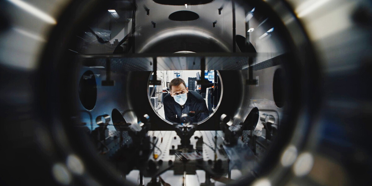 Masked technician inspects equipment at Amazon Leo manufacturing facility