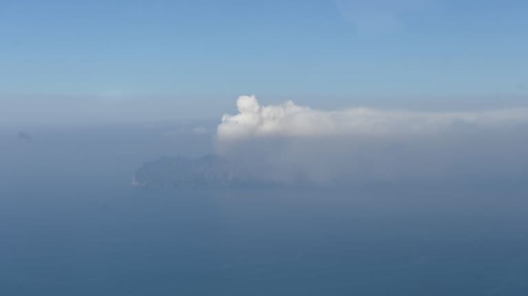 White steam and gas plume from Whakaari/White Island, with a lower hazy plume carrying a small amount of volcanic ash.