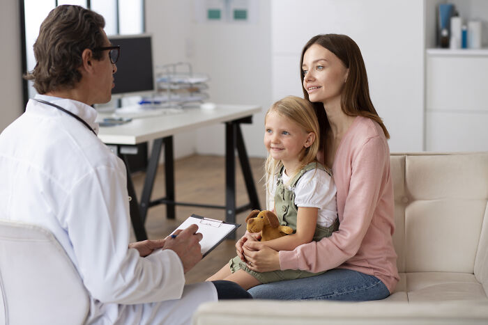A doctor talking to a mother and child in a medical office, listening to their story.