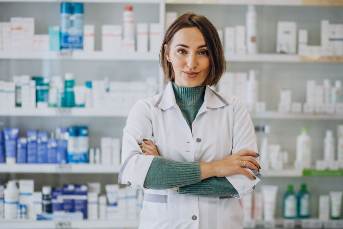 A female medical professional in a lab coat standing in a pharmacy.