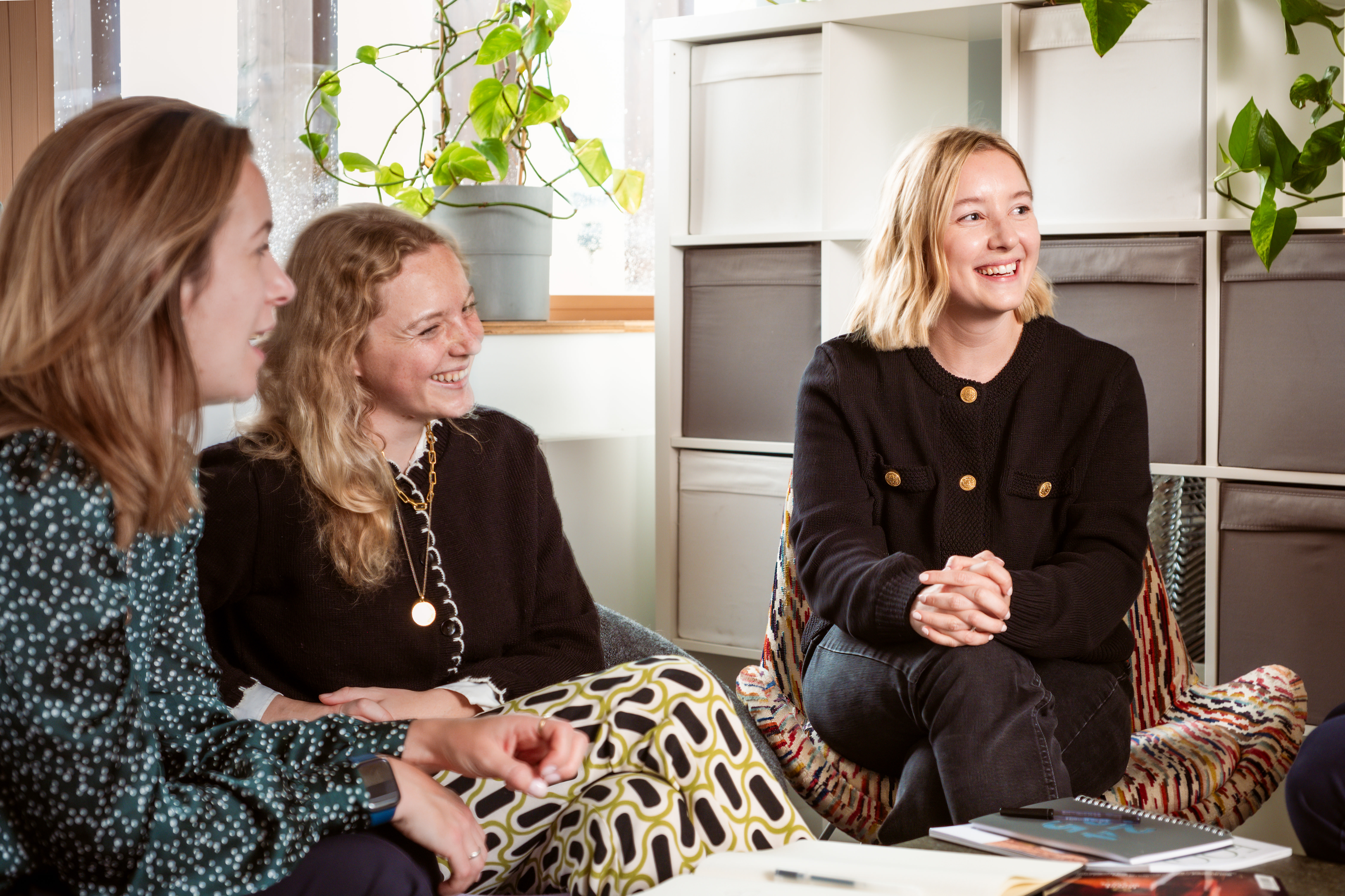Three women sitting and talking in an office.