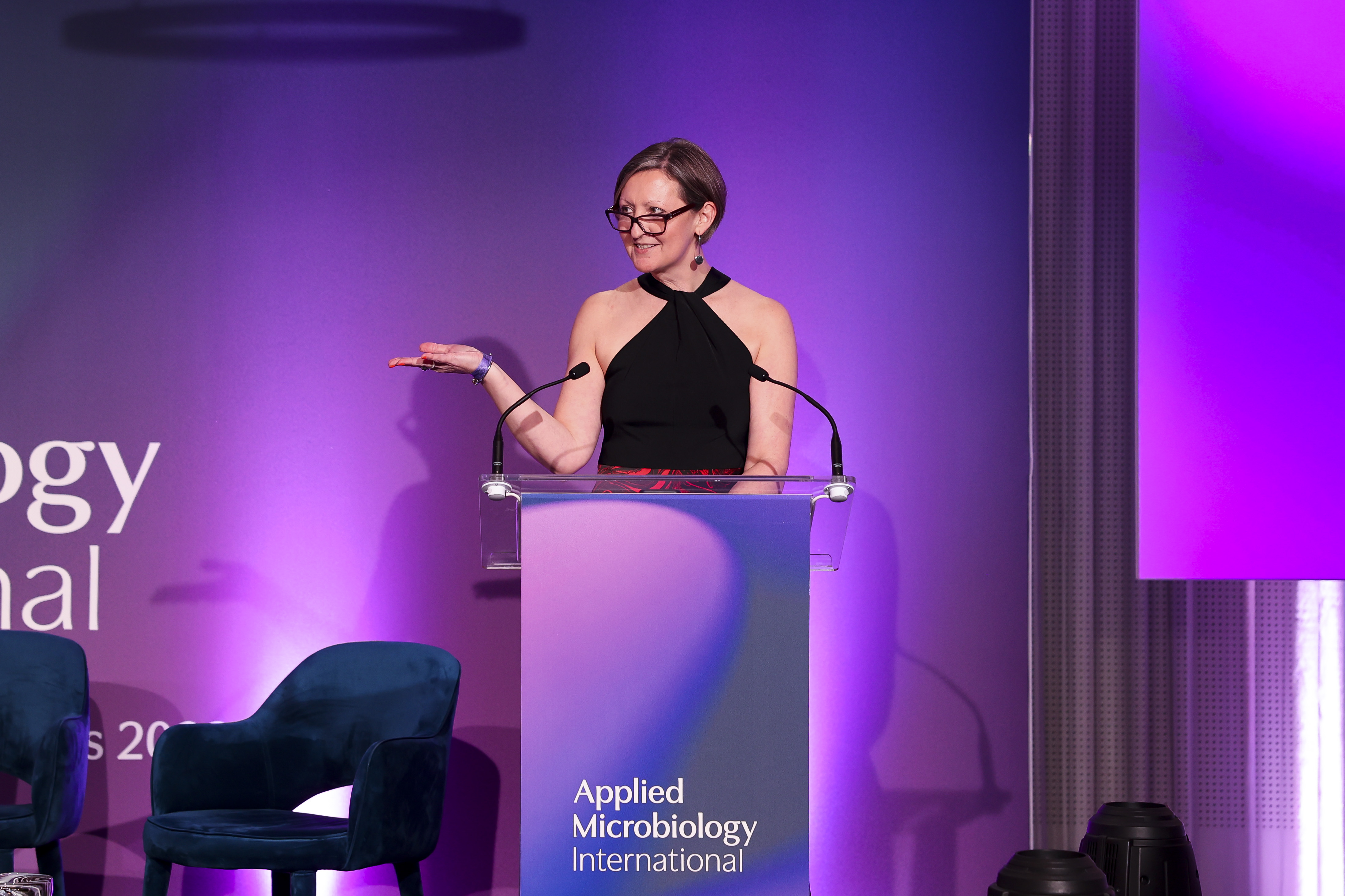 Dr. Lucy Harper speaking at a podium.