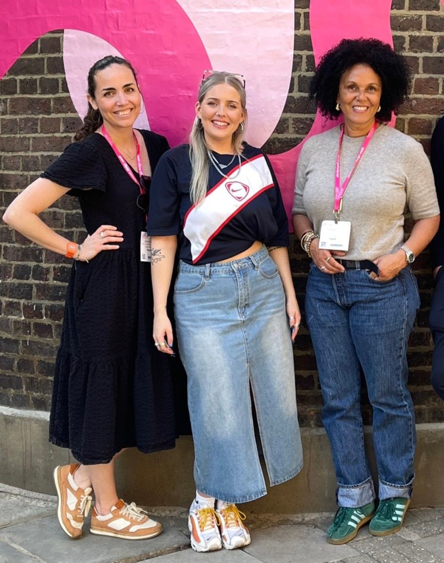 Three women standing in front of a brick wall.