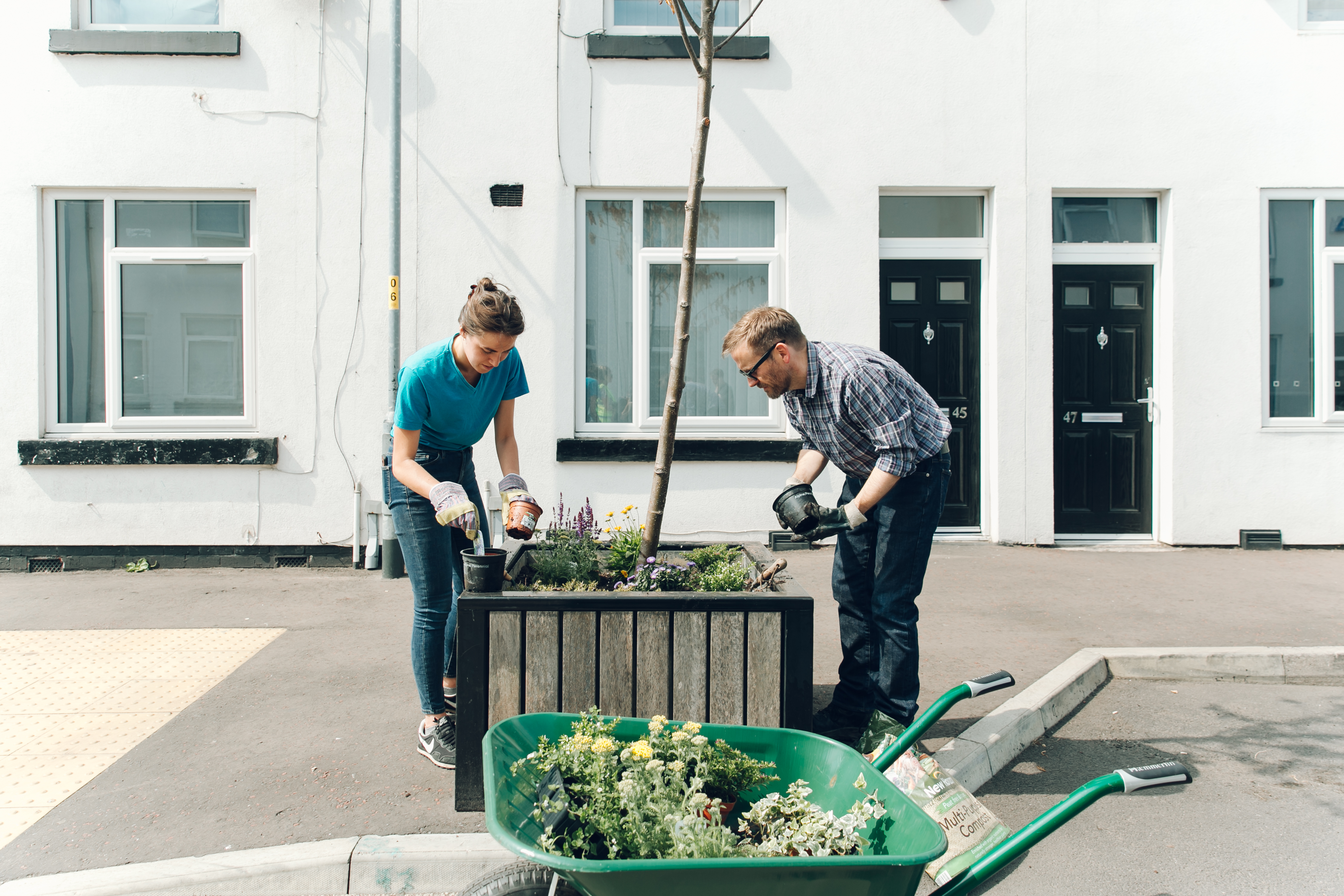 Two people planting flowers in a planter.
