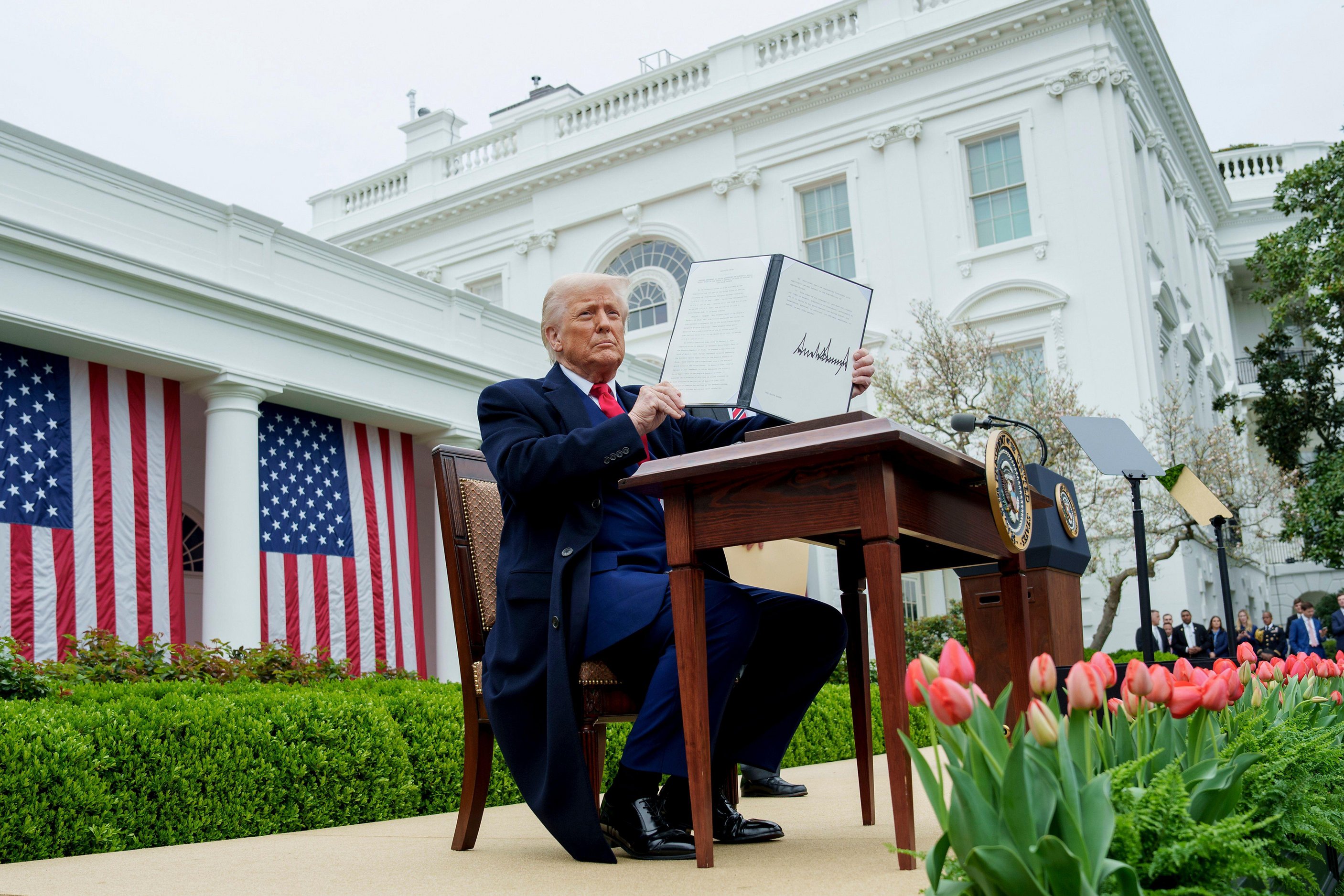 President Trump holding a signed executive order at the White House Rose Garden.