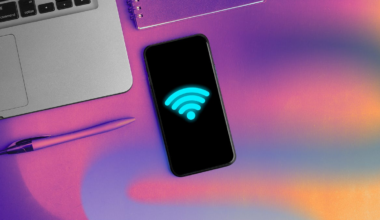 smartphone with Wi-Fi logo in neon blue next to laptop