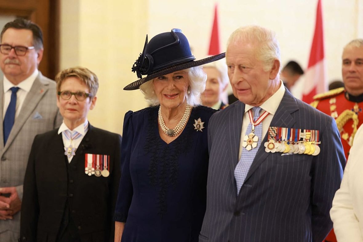 Two people stand next to one another as other people stand nearby.