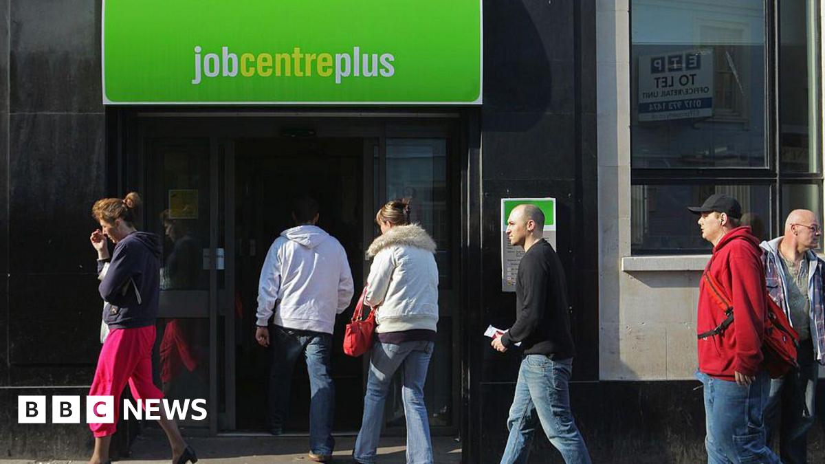 five people queue up to enter a job centre, while another woman walks past the front door