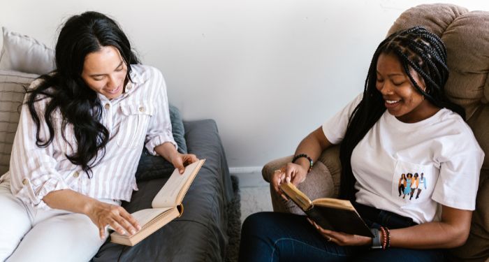 two young femme-presenting people each reading a book