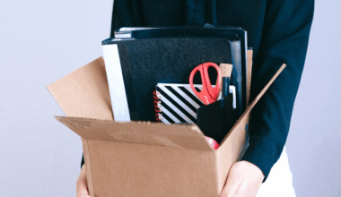 Person holding an open box full of office supplies
