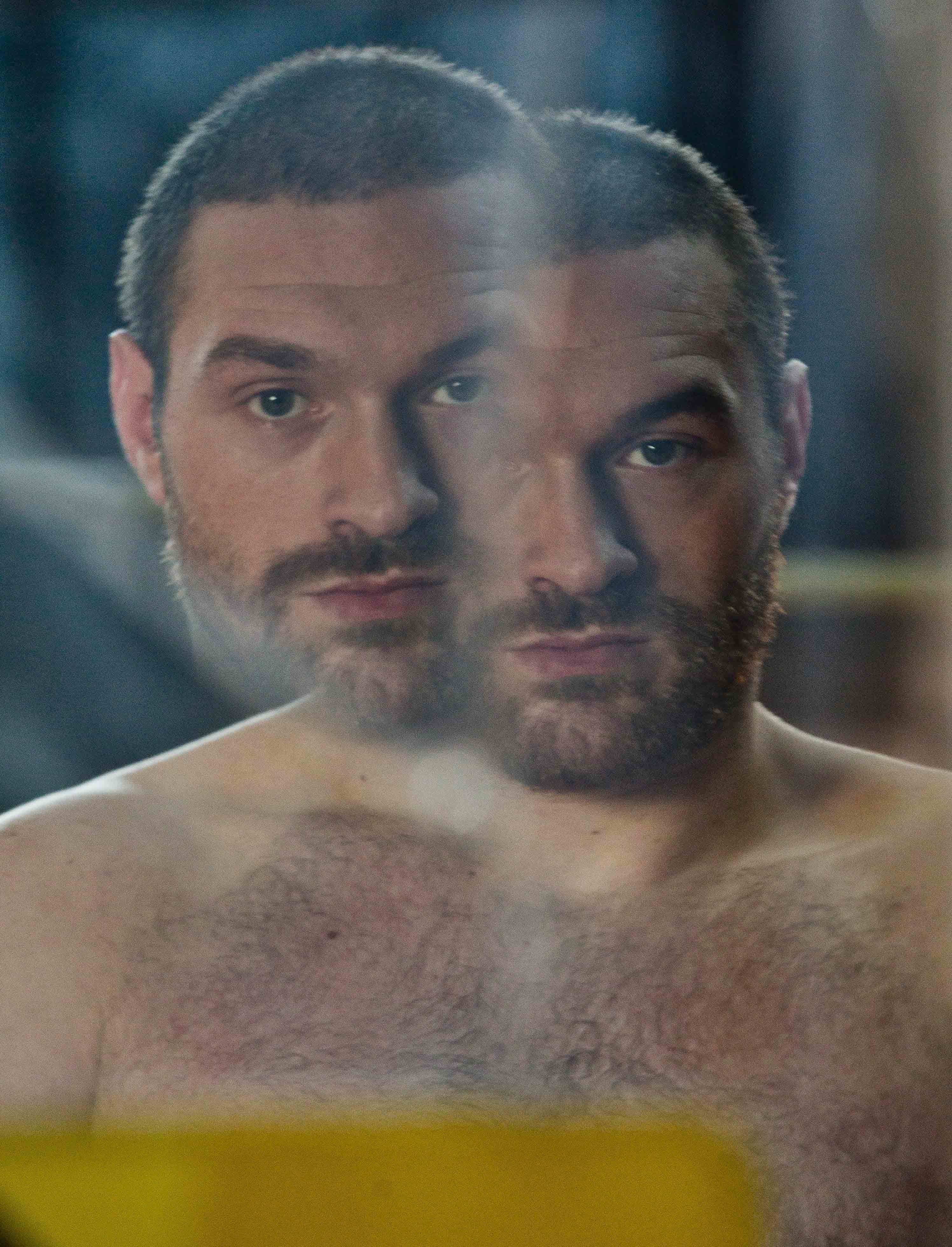 Portrait of a shirtless man with a beard, his face appearing doubled.