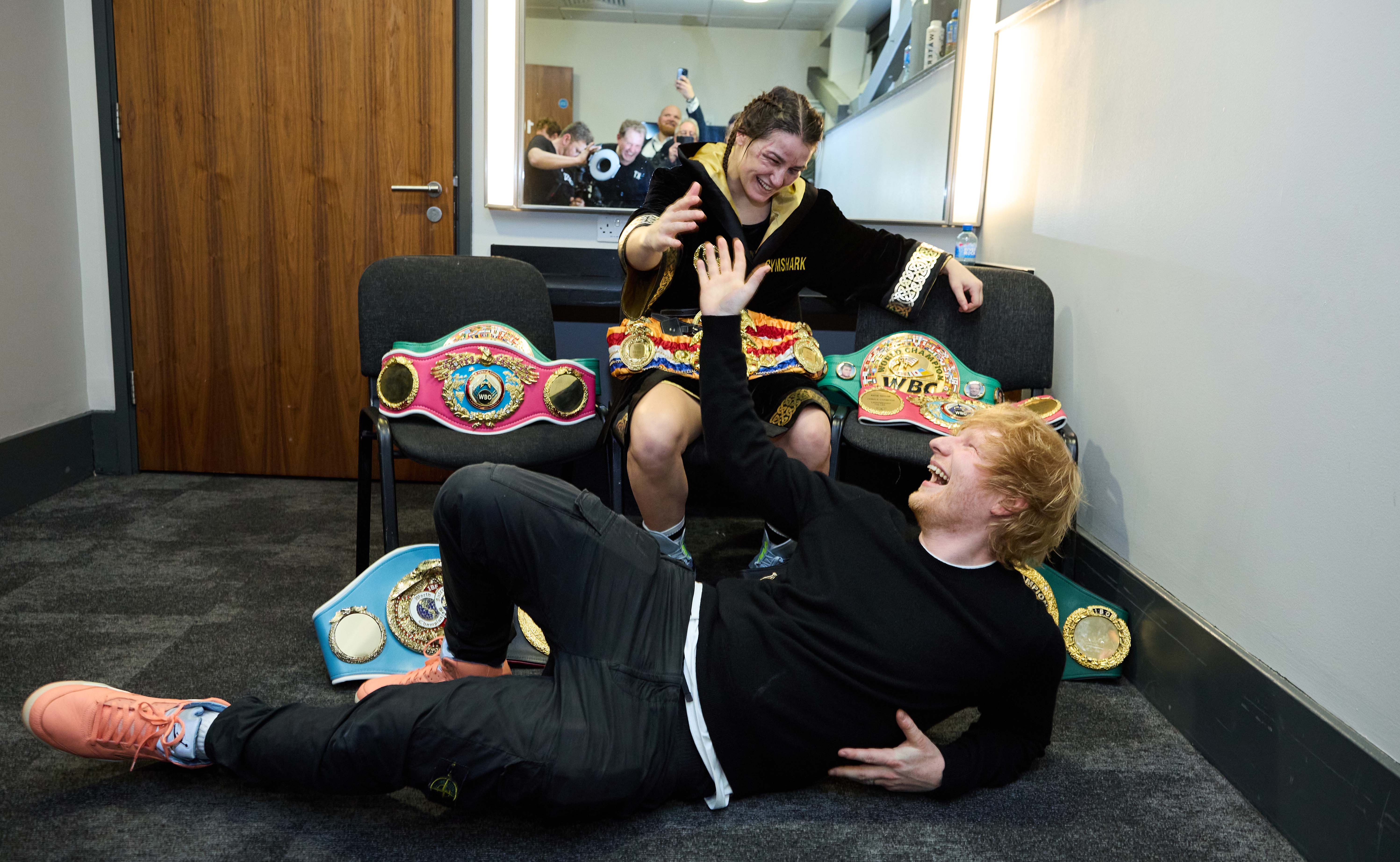 Katie Taylor and Ed Sheeran celebrating with championship belts.