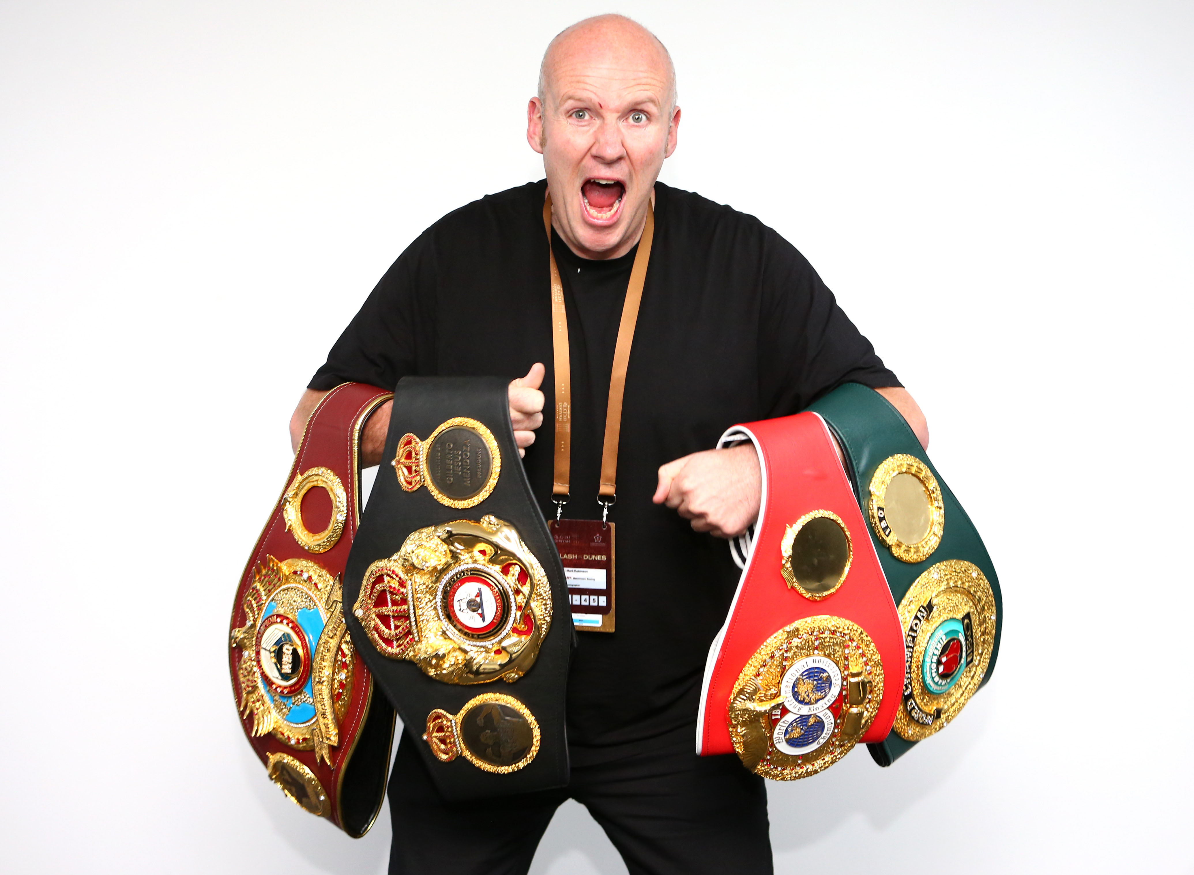 Man holding multiple boxing championship belts.