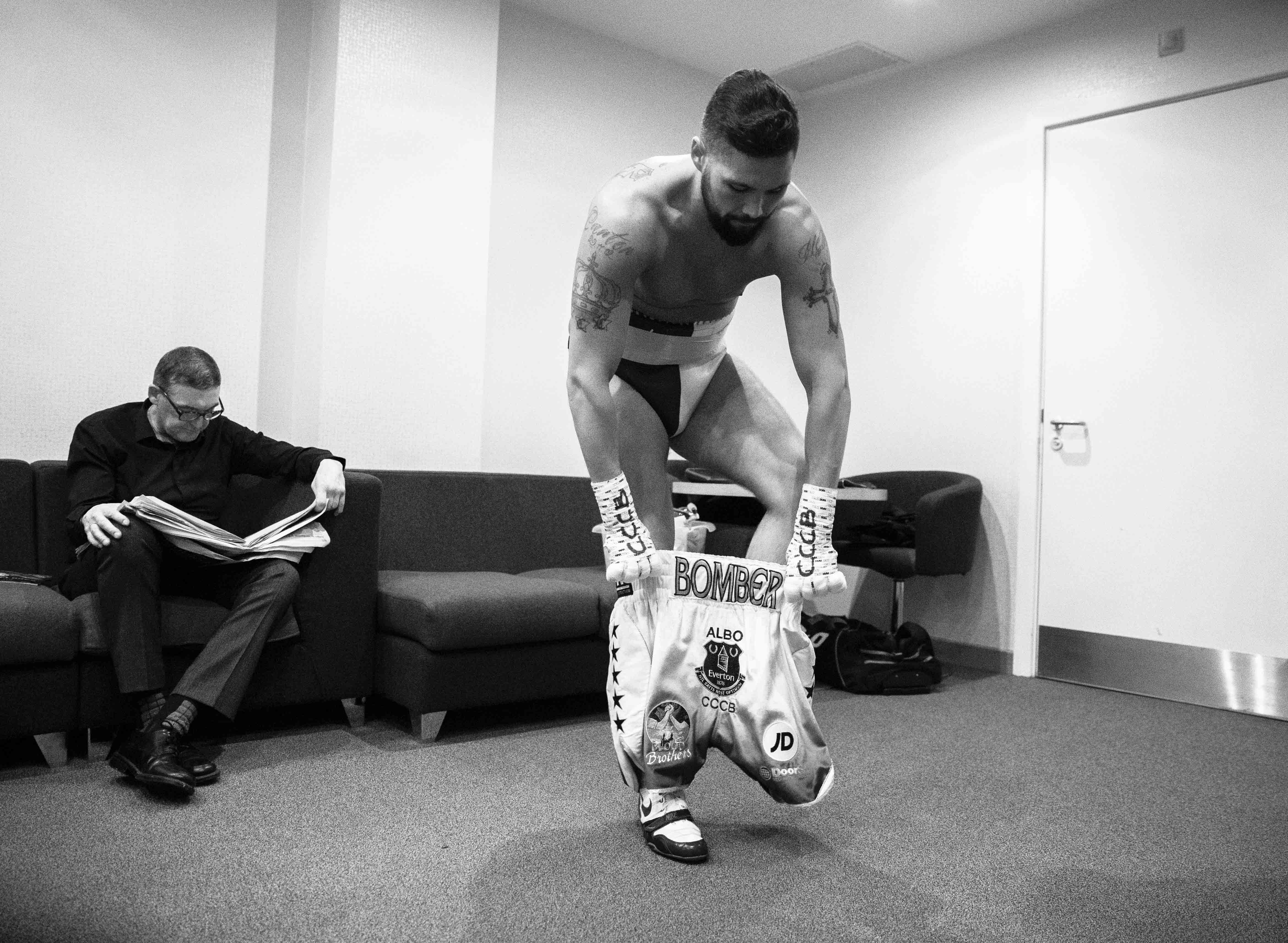 Black and white photo of a boxer putting on his boxing shorts.