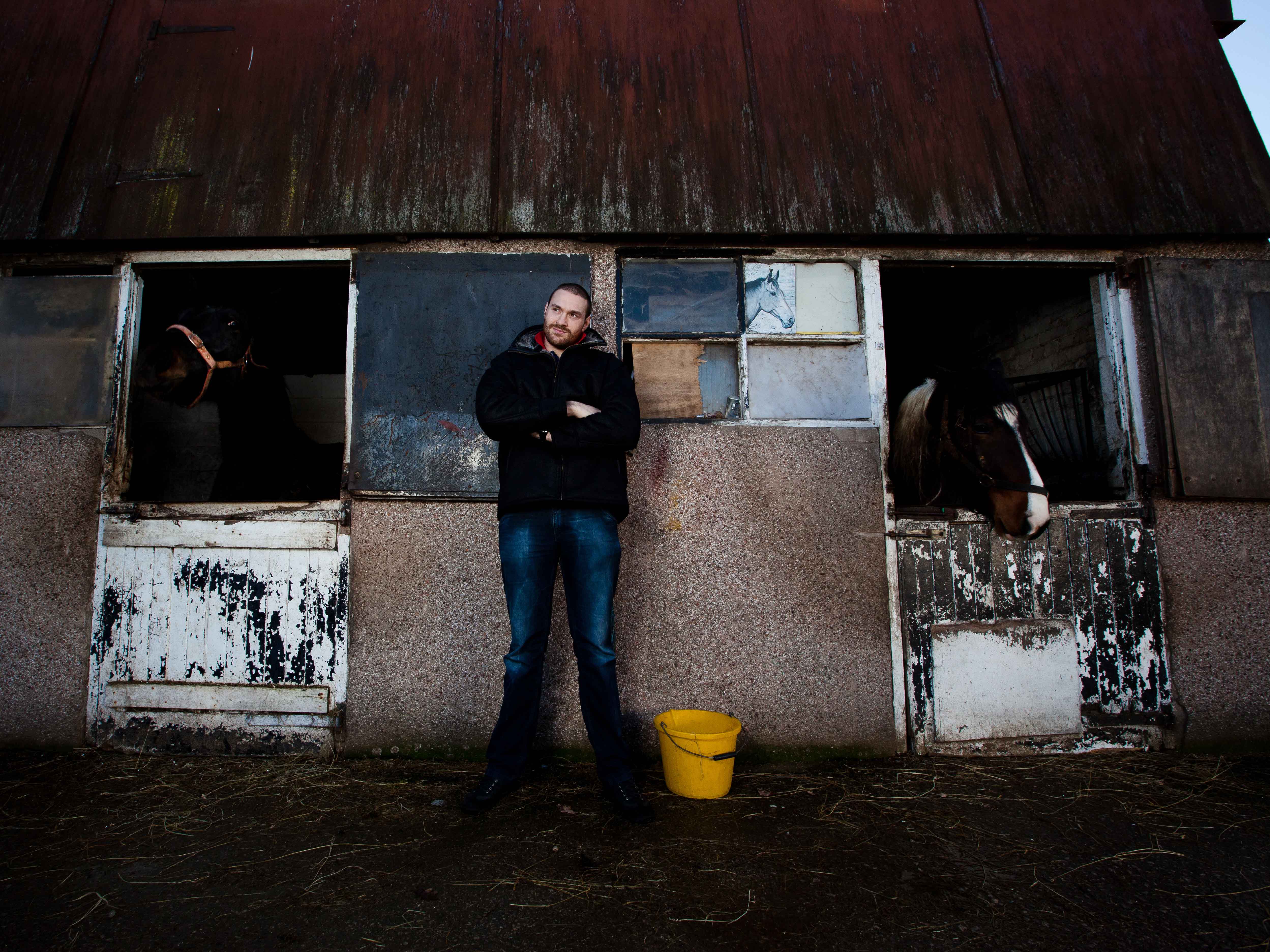 Tyson Fury standing between two horse stables.