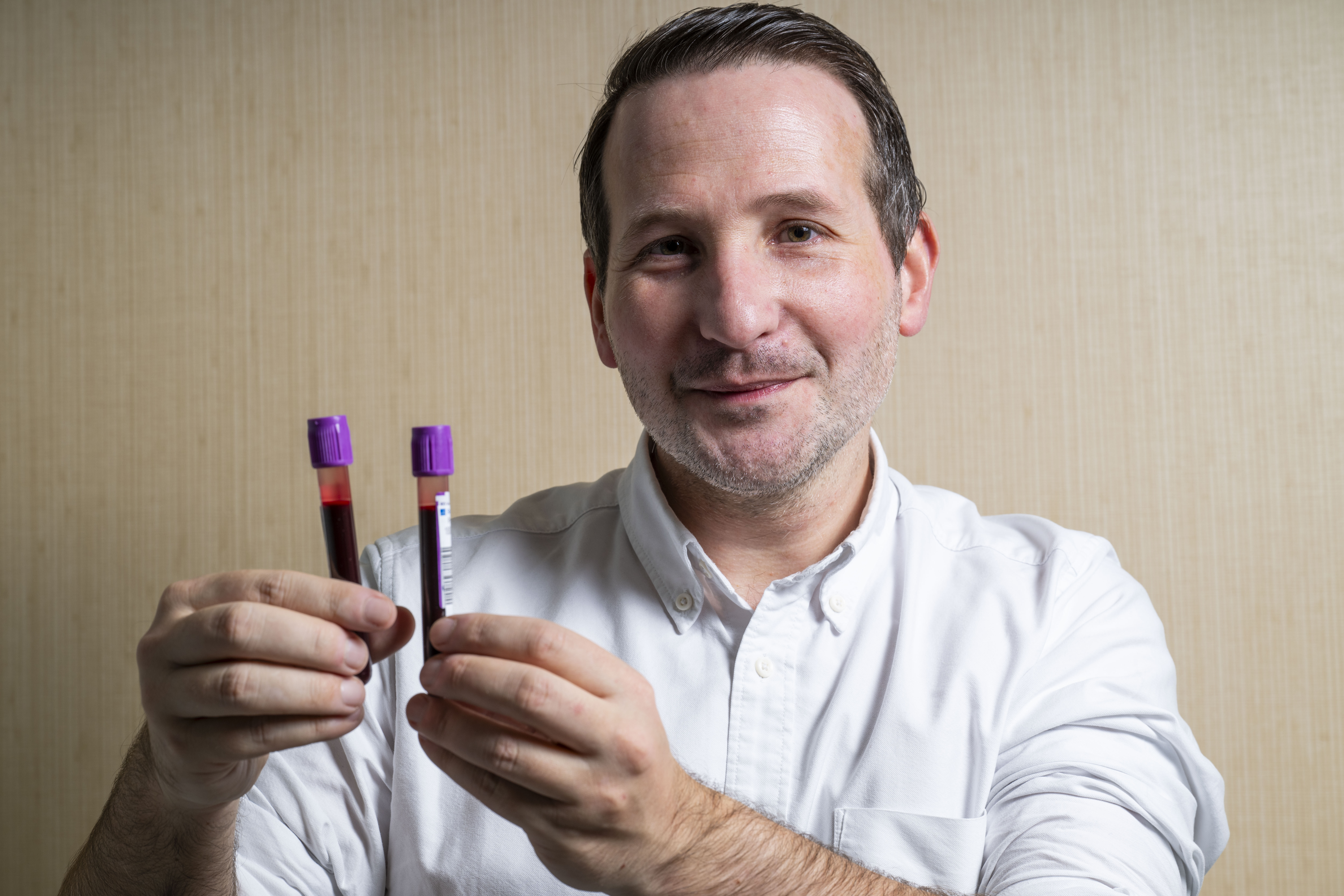 Man holding two blood sample tubes.