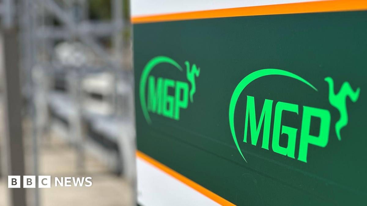 A sign in the pitlane at the grandstand featuring the MGP logo, which includes a semi-circle with a three legs of Mann emblem at one end.