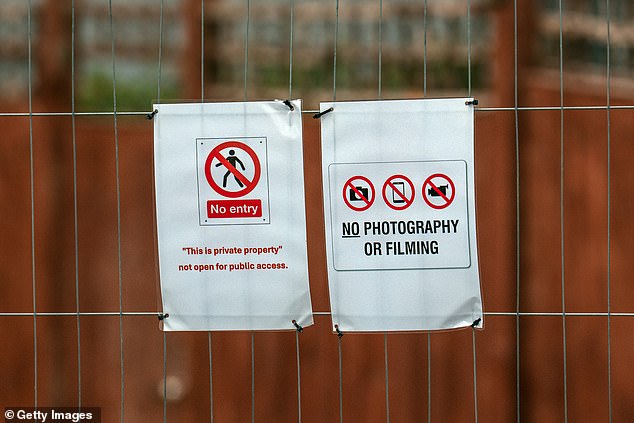 The hotel has been put behind fencing to separate it from protesters (pictured: notices attached to a security fence)