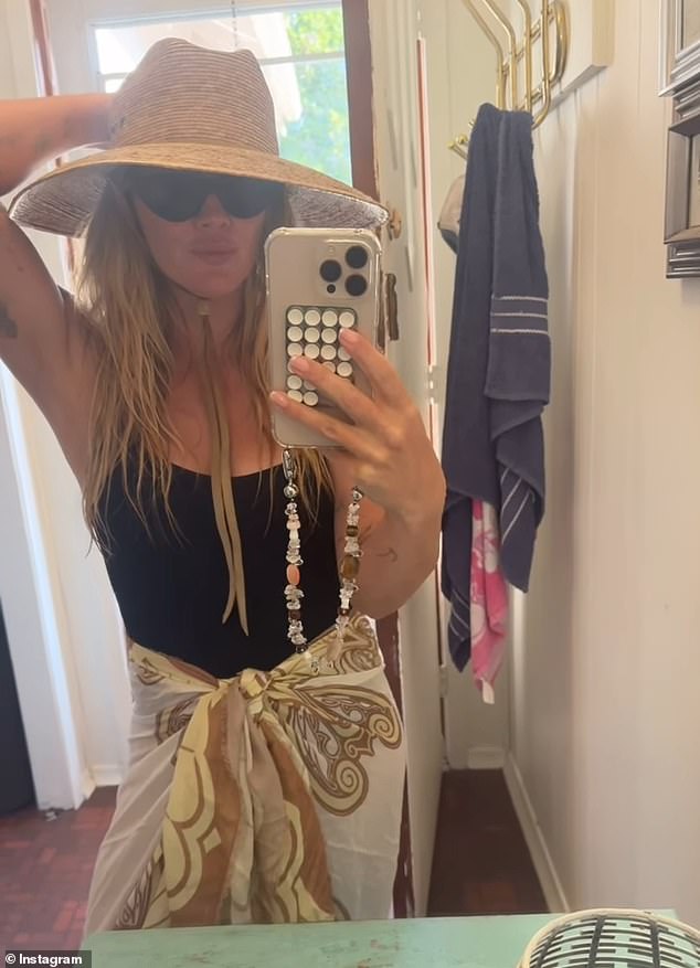 In this image she had on a black swimsuit with a beige wrap and a hat