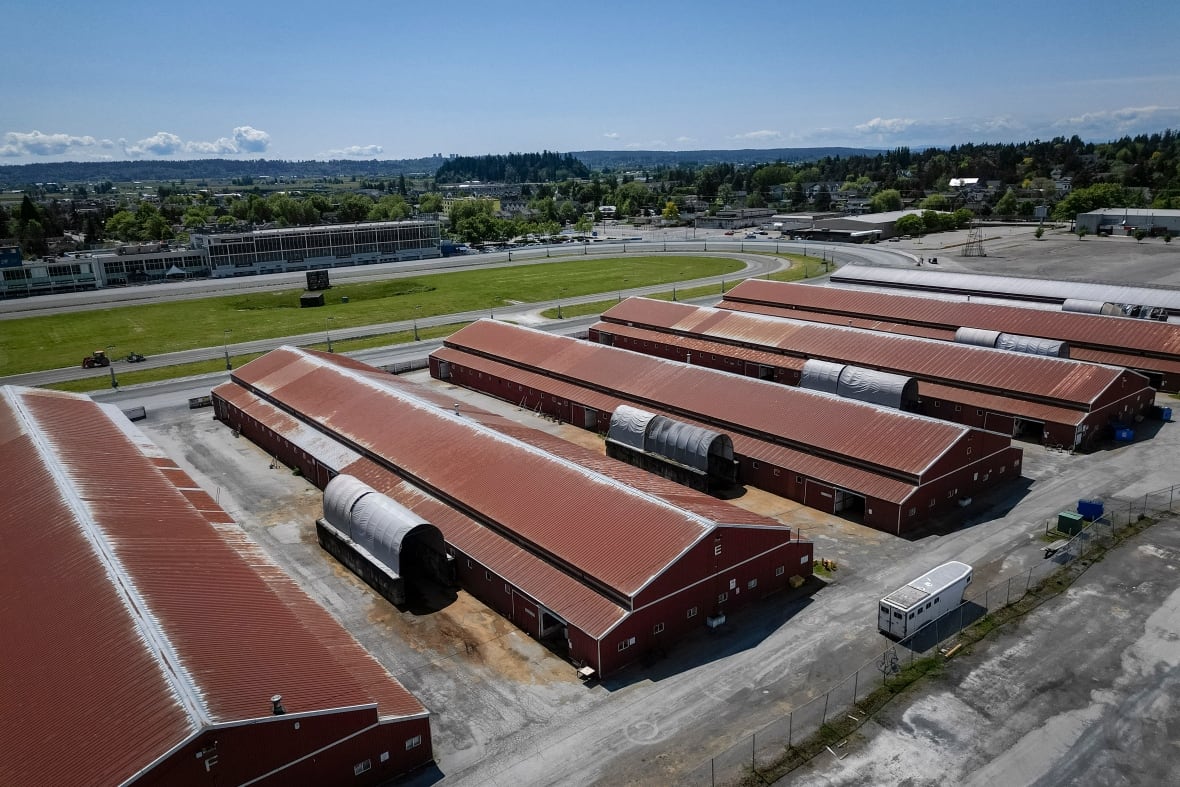 A succession of low, long barns topped with red roofs.