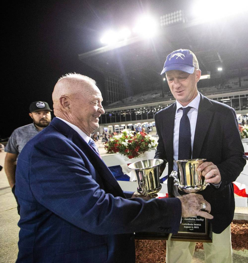MIKAELA MACKENZIE / FREE PRESS
Randy Howg (left) hands trophies to Attack trainer Craig Robert Smith, who won after Take Charge Tom was disqualified Monday night at the 77th Manitoba Derby. This was the first time in the running of the Derby the winner has been disqualified.