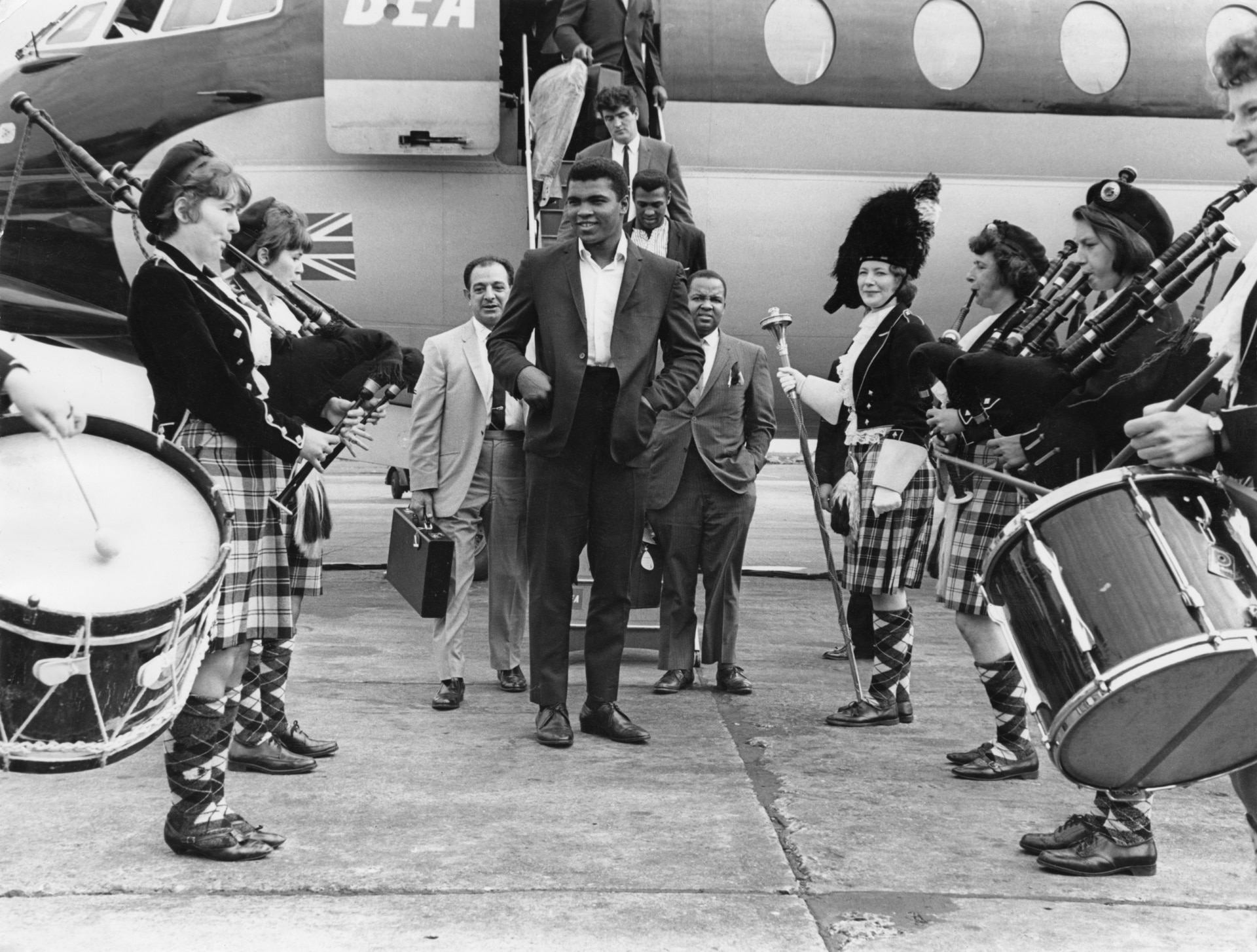 American WBC world heavyweight boxing champion Muhammad Ali is greeted by a traditional Scottish pipe band on his arrival at Glasgow Airport, 18th August 1965. Ali is in the city for a series of exhibition matches.  (Photo by Daily Express/Pictorial Parade/Archive Photos/Getty Images)
