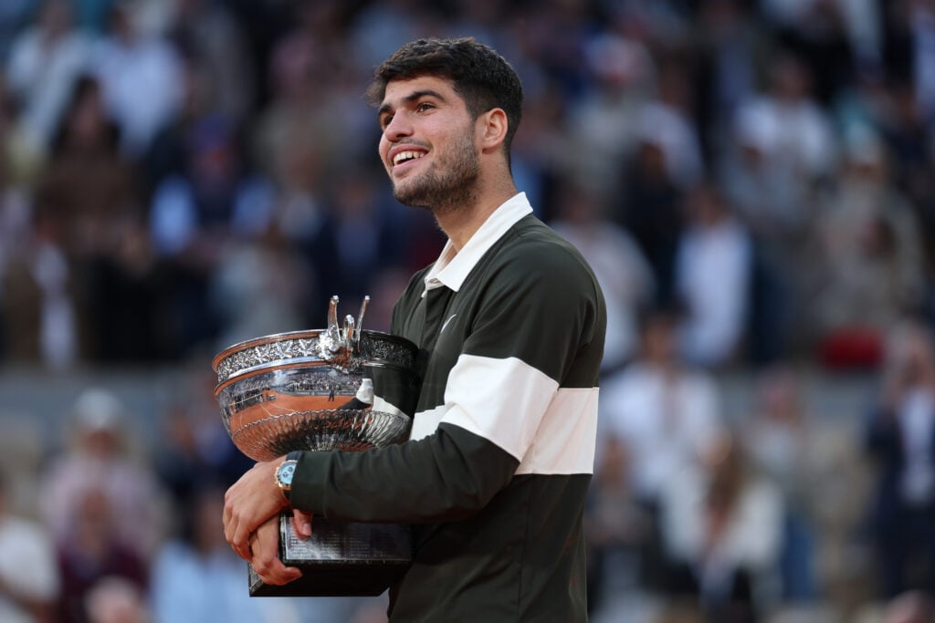 Carlos Alcaraz poses with the French Open title after winning in 2025