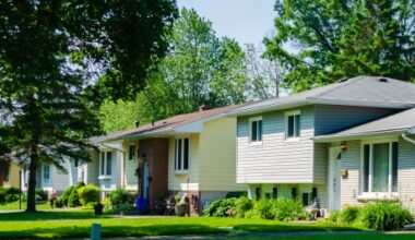Photo: Panorama of sunlit small suburban houses on a tree-lined street in the summer