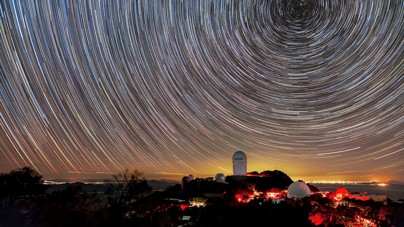 DESI maps distant objects to study dark energy. The instrument is installed on the Mayall Telescope, shown here beneath star trails.