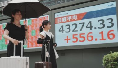Pedestrians walk in front of an electronic quotation board displaying the Nikkei Stock Average