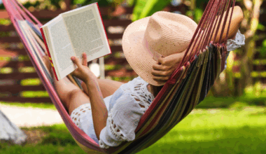 a photo of someone wearing a floppy hat and reading in a hammock