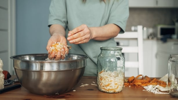 woman prepares pickled white cabbage, transfers the cabbage from a metal bowl into a jar. Fermented product