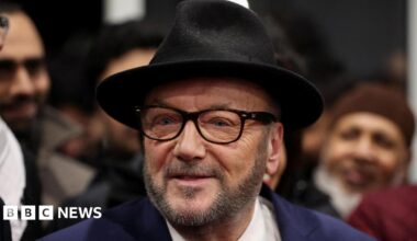 George Galloway, leader of the Workers Party of Britain wears a black felt fedora, raybans and a navy blazer.