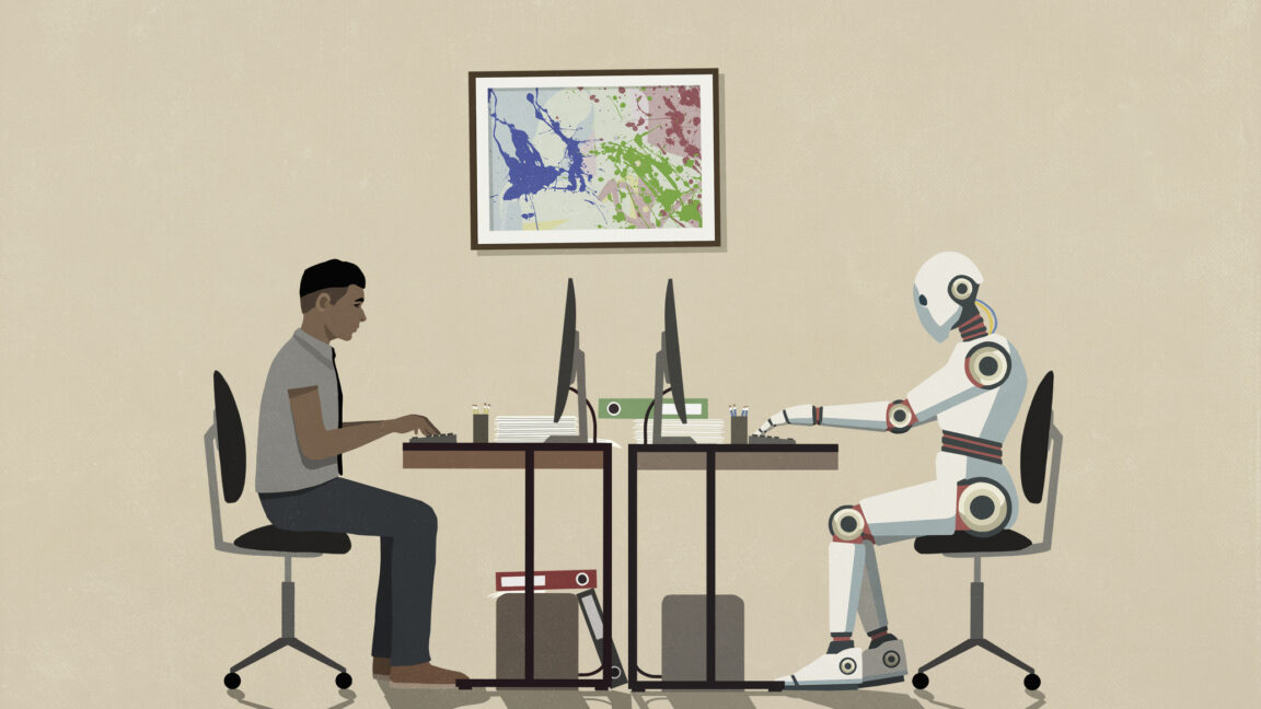 Man and humanoid robot working face to face at computers
