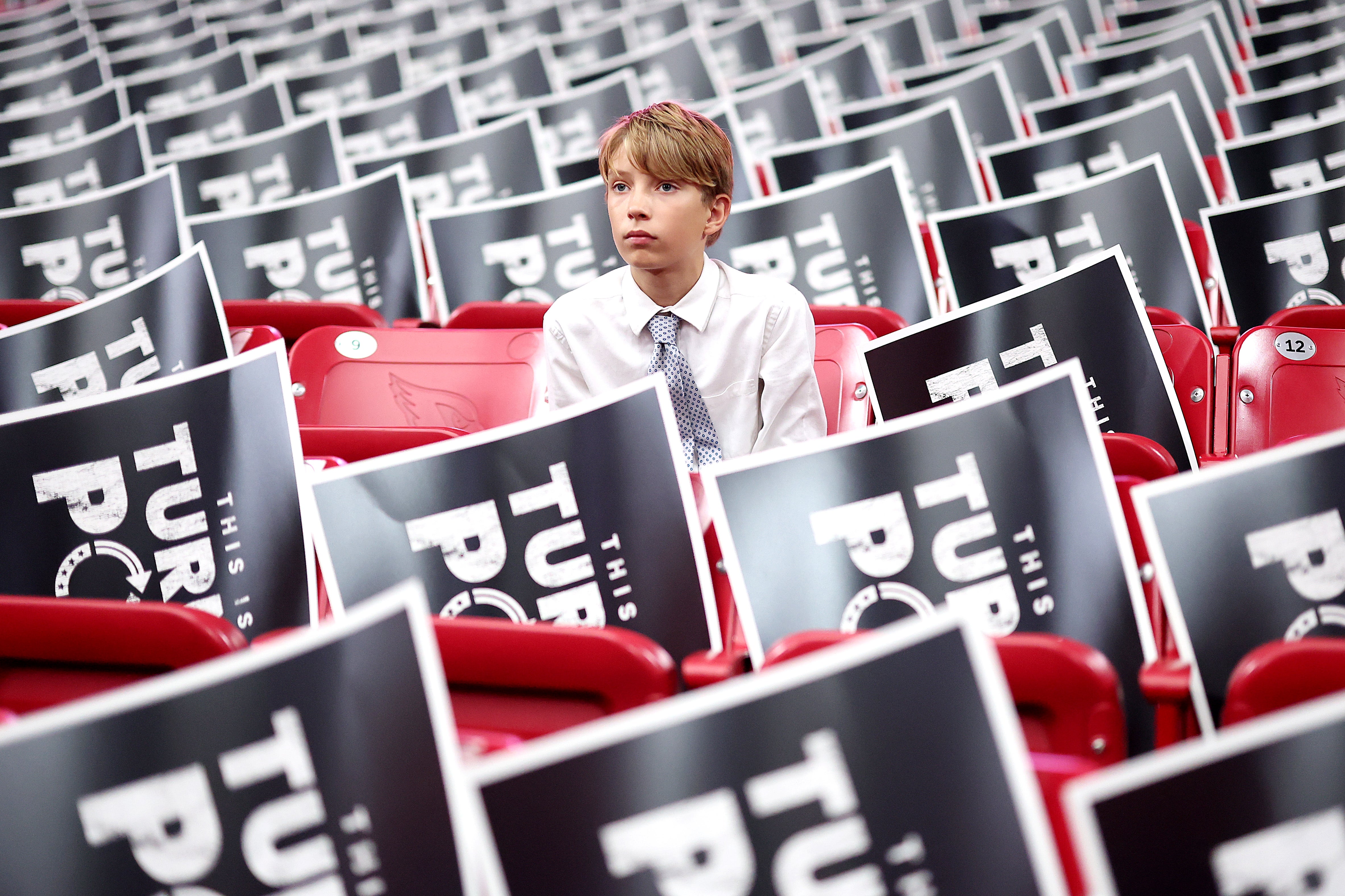 A young attendee sits in the stands ahead of the memorial service for political activist Charlie Kirk