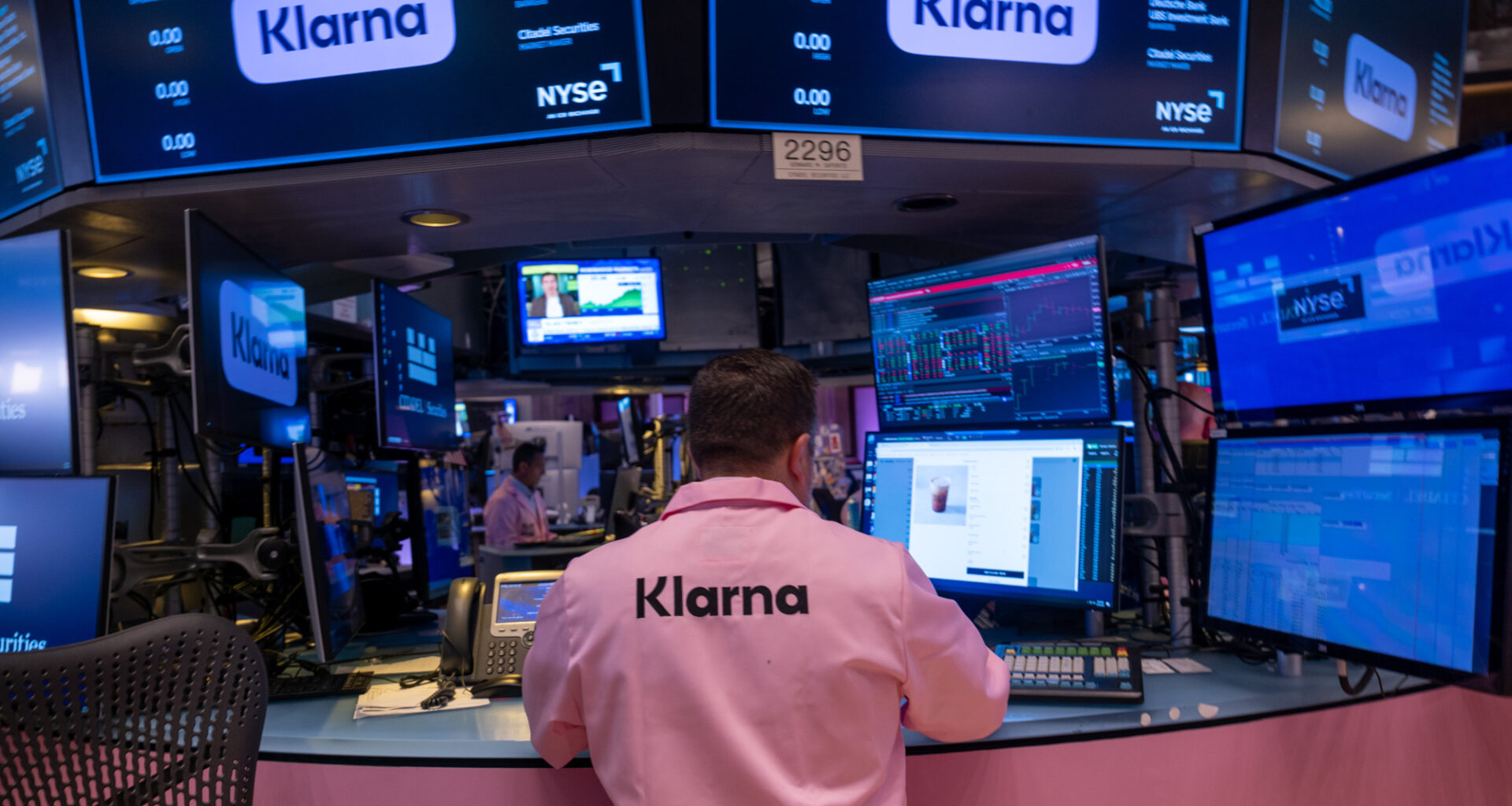 A man wearing a pink shirt with 'Klarna' written on the back