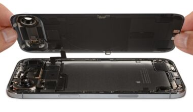 An iPhone display is removed to reveal a battery on the bottom and a logic board and camera on top