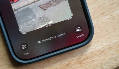 Close-up of a smartphone screen showing a photo of a street with a sidewalk and traffic cones. Below the photo are three interface options: a speech bubble icon labeled