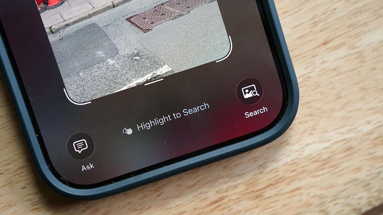 Close-up of a smartphone screen showing a photo of a street with a sidewalk and traffic cones. Below the photo are three interface options: a speech bubble icon labeled