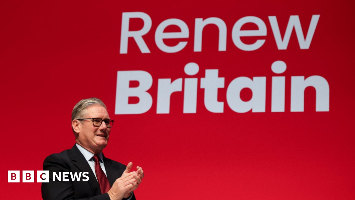 Sir Keir Starmer stands in front of a giant red screen with the slogan Renew Britain. He is wearing a dark suit with a white shirt and a red tie. He is applauding Chancellor Rachel Reeves, not shown.