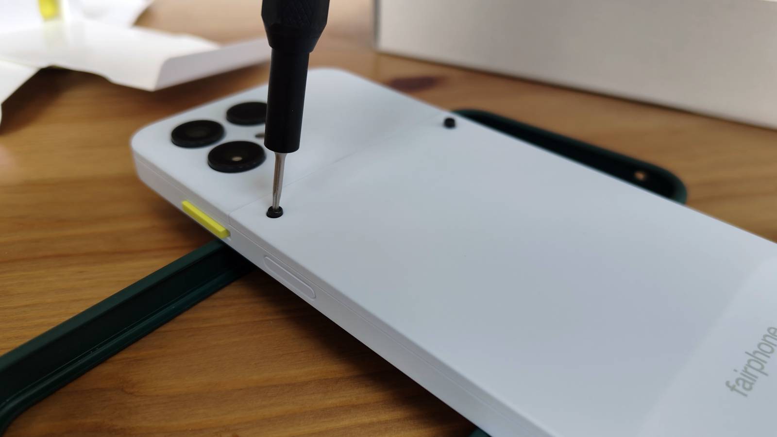 The Fairphone 6 with a screwdriver loosening a screw.