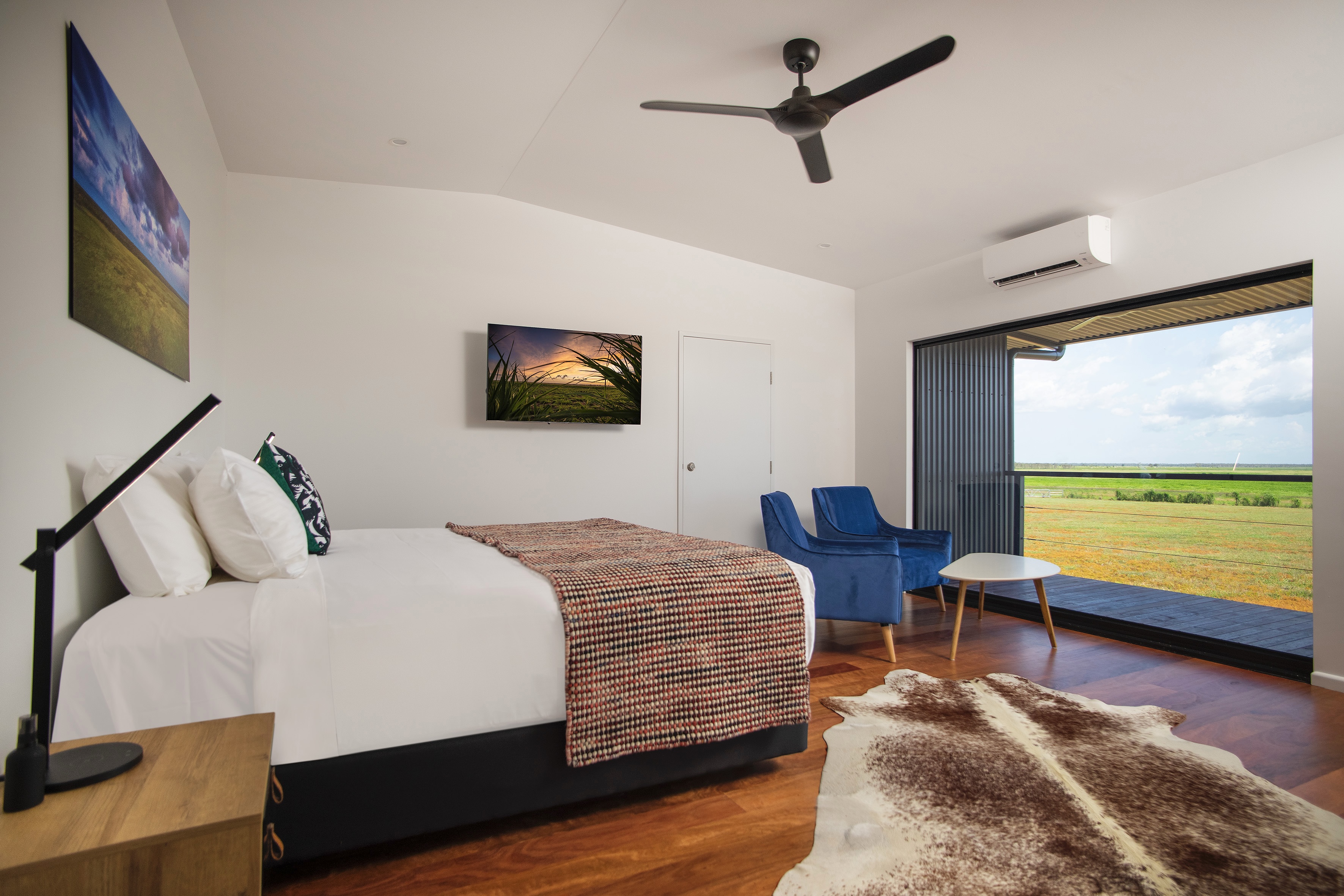 Finniss River Lodge bedroom with large sliding doors overlooking a green field.