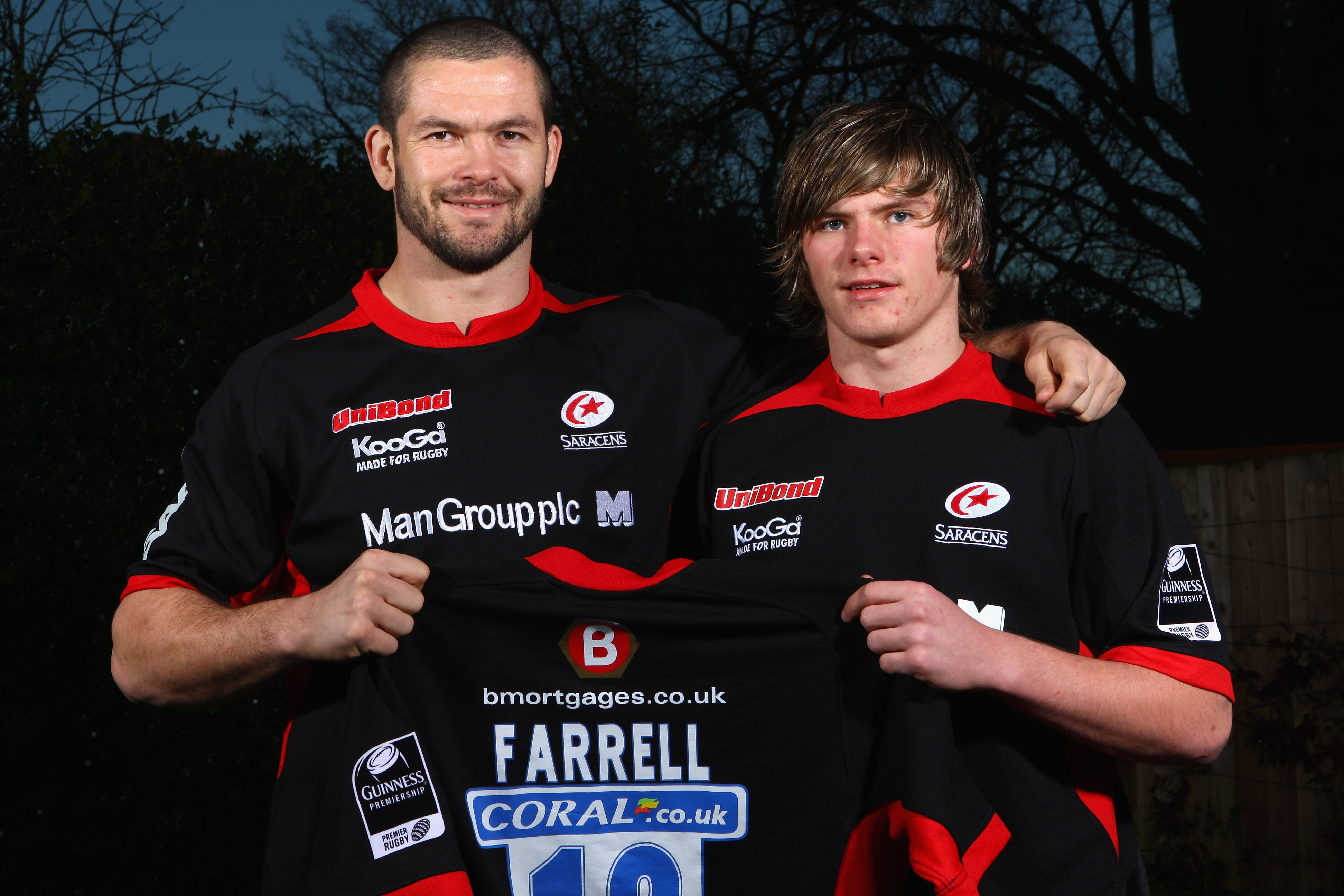 Andy Farrell (L) and Owen Farrell (R) in black and red Saracens rugby jerseys.